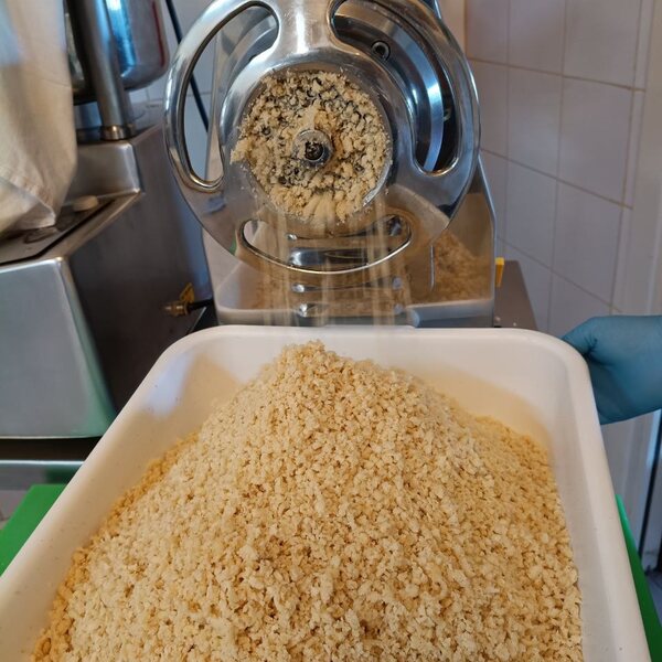 Mandorle macinate che cadono a cascata dal mulino nella vasca